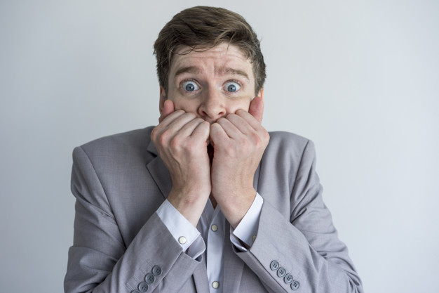 Shocked scared young businessman looking at camera