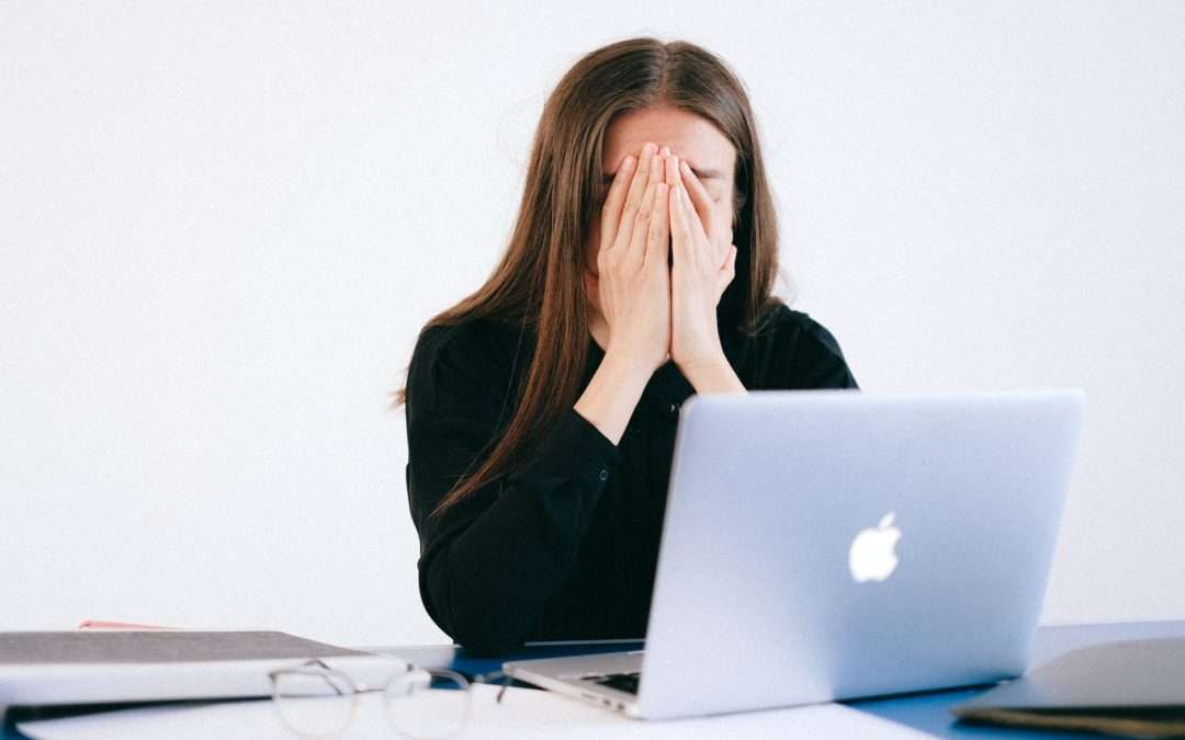 woman with hands on her face in front of a laptop