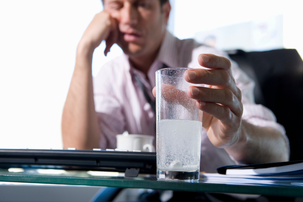 Businessman,In,Office,With,Headache,Dissolving,Tablets,In,Glass,Of